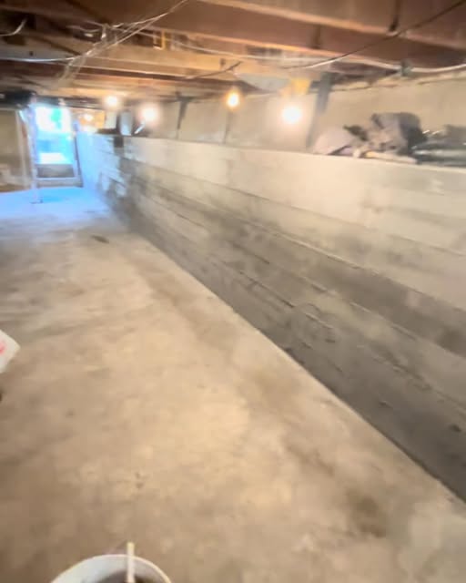 Sister foundation wall and waterproofing work inside a full-size basement